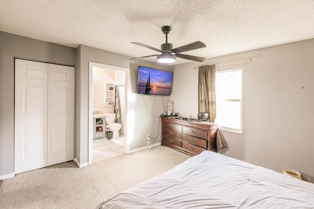 bedroom featuring connected bathroom, a closet, light carpet, ceiling fan, and a textured ceiling