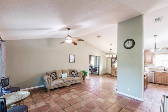 living room featuring a textured ceiling, vaulted ceiling, tile patterned floors, ceiling fan with notable chandelier, and sink