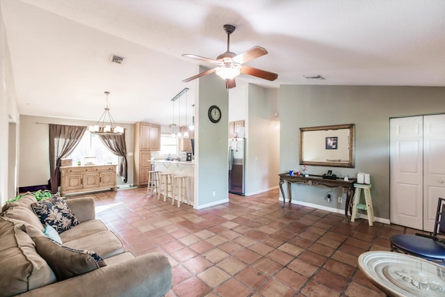 living room featuring ceiling fan with notable chandelier, vaulted ceiling, and dark tile patterned flooring