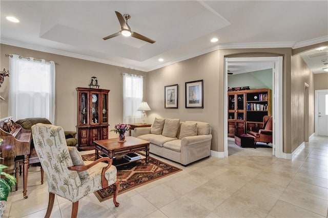 tiled living room featuring ceiling fan, ornamental molding, and a tray ceiling