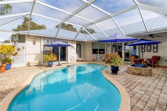 view of swimming pool with glass enclosure, a patio area, and an outdoor fire pit