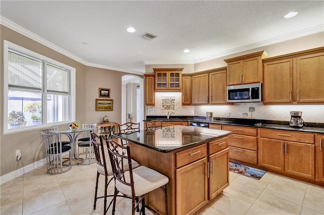 kitchen featuring a center island, light tile patterned flooring, ornamental molding, and dark stone counters