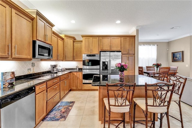 kitchen with dark stone counters, crown molding, a center island, and stainless steel appliances