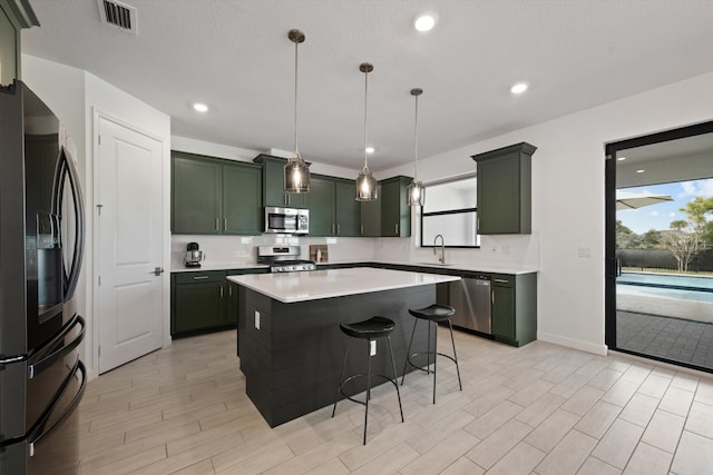 kitchen with stainless steel appliances, a healthy amount of sunlight, hanging light fixtures, and a center island