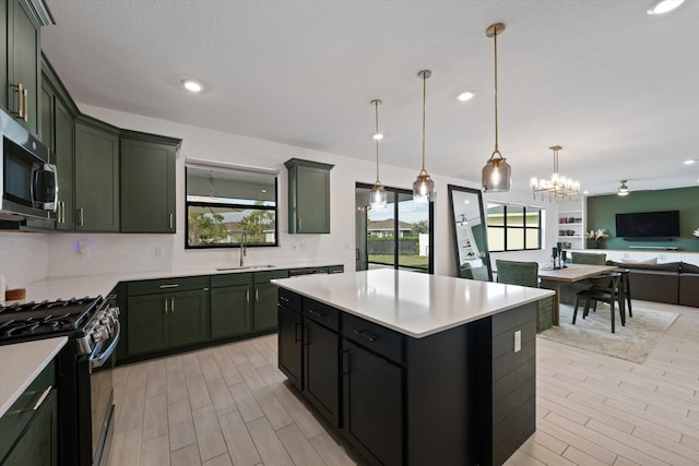 kitchen featuring pendant lighting, range with gas stovetop, sink, backsplash, and a center island