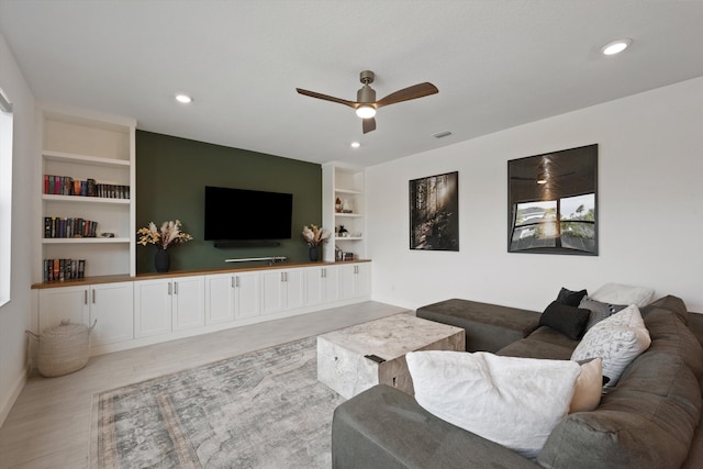 living room featuring light hardwood / wood-style flooring, ceiling fan, and built in shelves