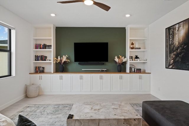 living room with light hardwood / wood-style flooring, ceiling fan, and built in shelves