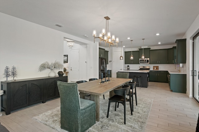 dining room featuring an inviting chandelier, sink, and light hardwood / wood-style floors