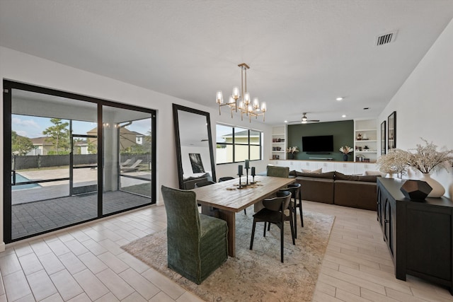 dining area with built in shelves and ceiling fan with notable chandelier