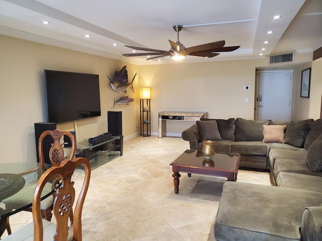 living room with a raised ceiling, ceiling fan, and ornamental molding