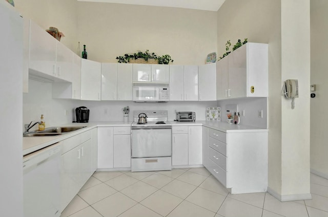 kitchen with sink, a high ceiling, light tile patterned flooring, white appliances, and white cabinets