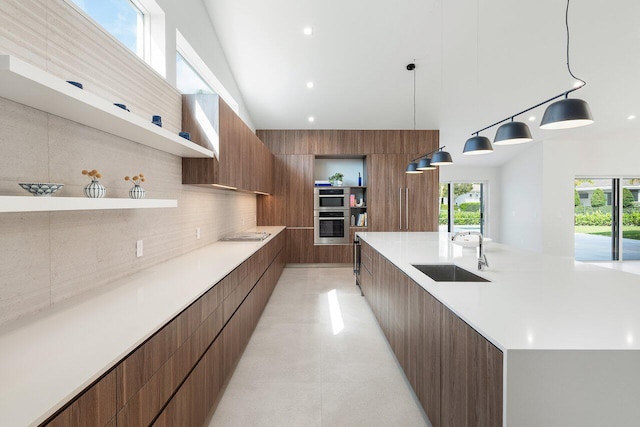 kitchen featuring sink, light tile patterned flooring, backsplash, hanging light fixtures, and multiple ovens