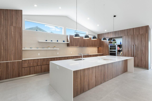 kitchen featuring vaulted ceiling, a spacious island, sink, decorative light fixtures, and backsplash