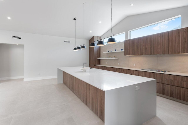 kitchen featuring lofted ceiling, a spacious island, sink, decorative light fixtures, and backsplash