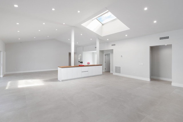 unfurnished living room with high vaulted ceiling and a skylight