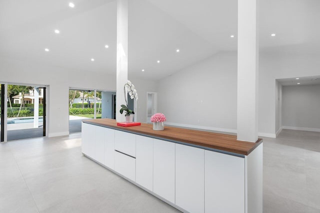 kitchen featuring high vaulted ceiling and white cabinets