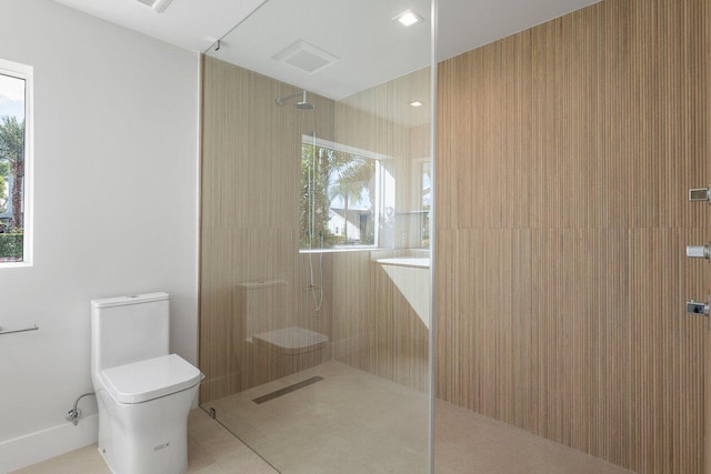 bathroom with tiled shower, tile patterned flooring, and toilet