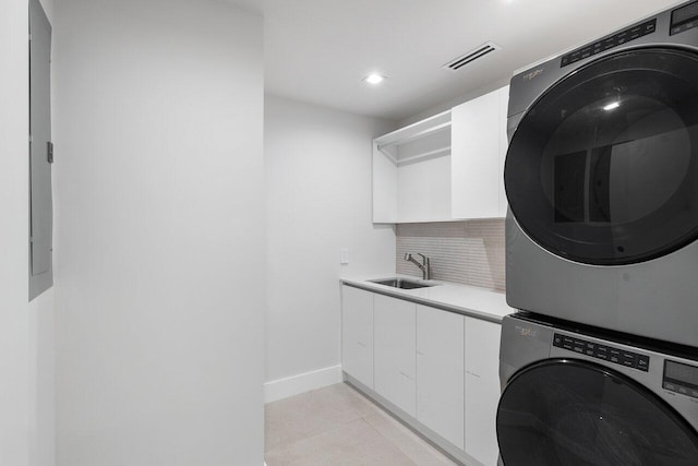 laundry room with sink, stacked washer / drying machine, and light tile patterned flooring