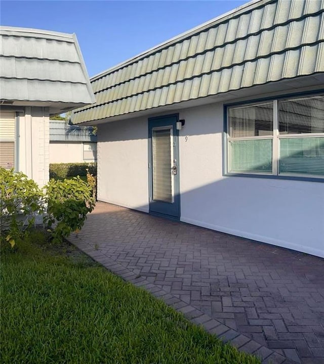 exterior space featuring mansard roof, a patio, and stucco siding