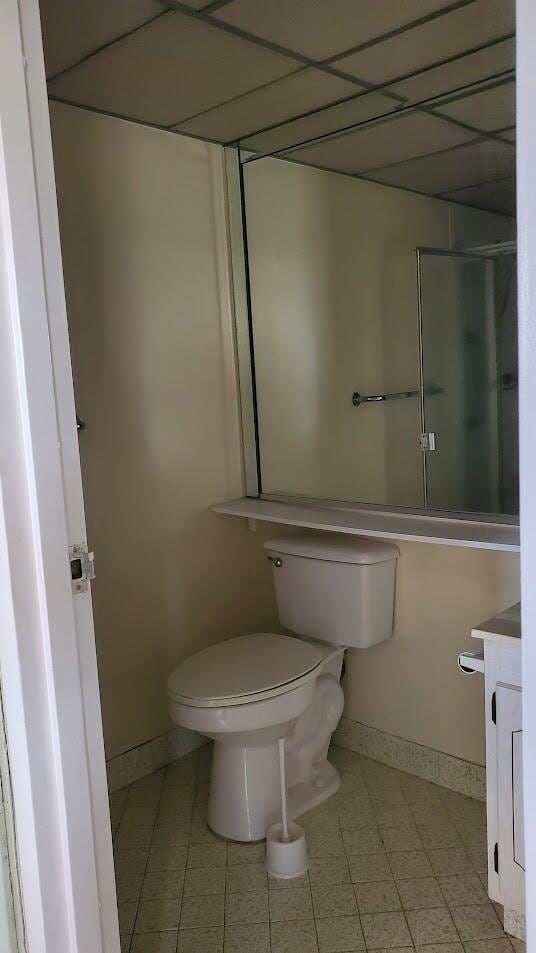 bathroom with a paneled ceiling, baseboards, vanity, and toilet