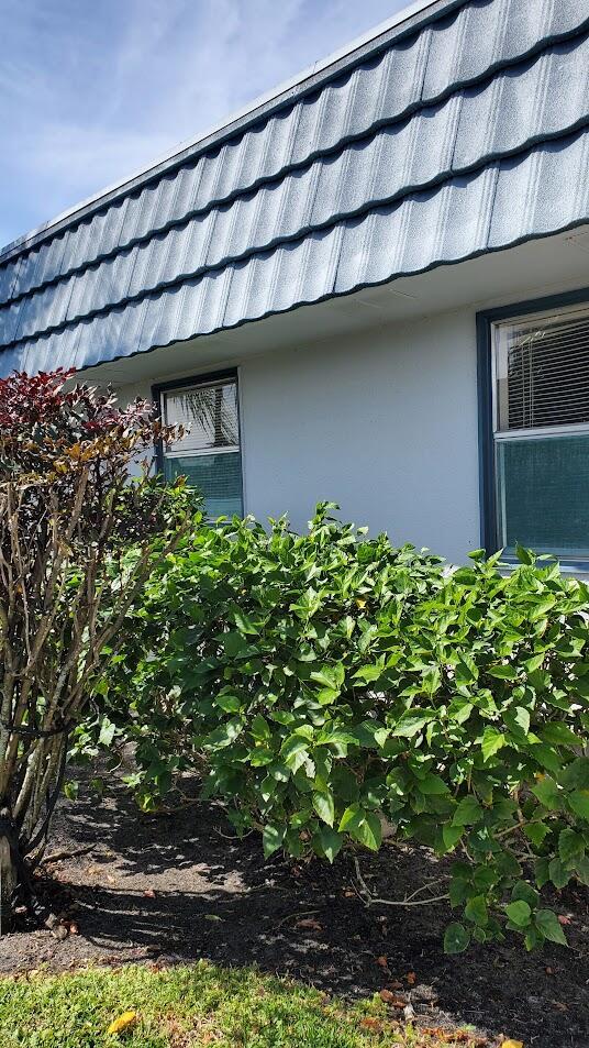 view of side of property with stucco siding and mansard roof