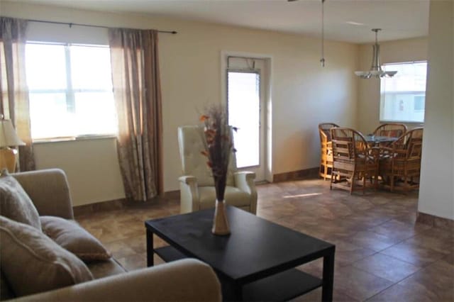 living area with baseboards and a notable chandelier