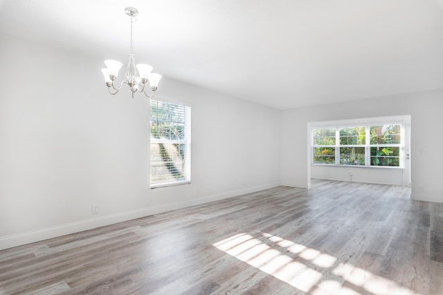 spare room with light hardwood / wood-style flooring and a notable chandelier