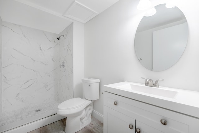 bathroom featuring a baseboard heating unit, wood-type flooring, tiled shower, toilet, and vanity