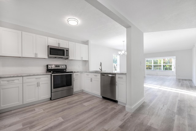 kitchen featuring backsplash, white cabinetry, light wood-type flooring, and appliances with stainless steel finishes