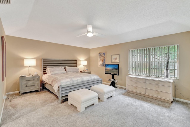 bedroom featuring light carpet, a textured ceiling, and ceiling fan