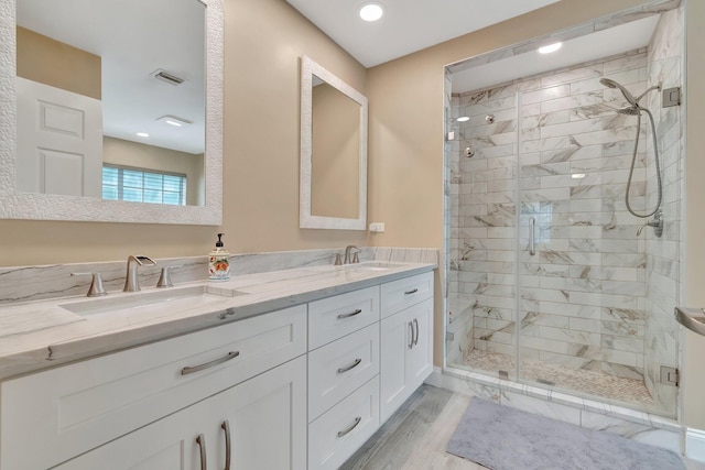 bathroom with hardwood / wood-style floors, vanity, and a shower with shower door