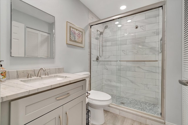 bathroom with wood-type flooring, vanity, toilet, and a shower with door