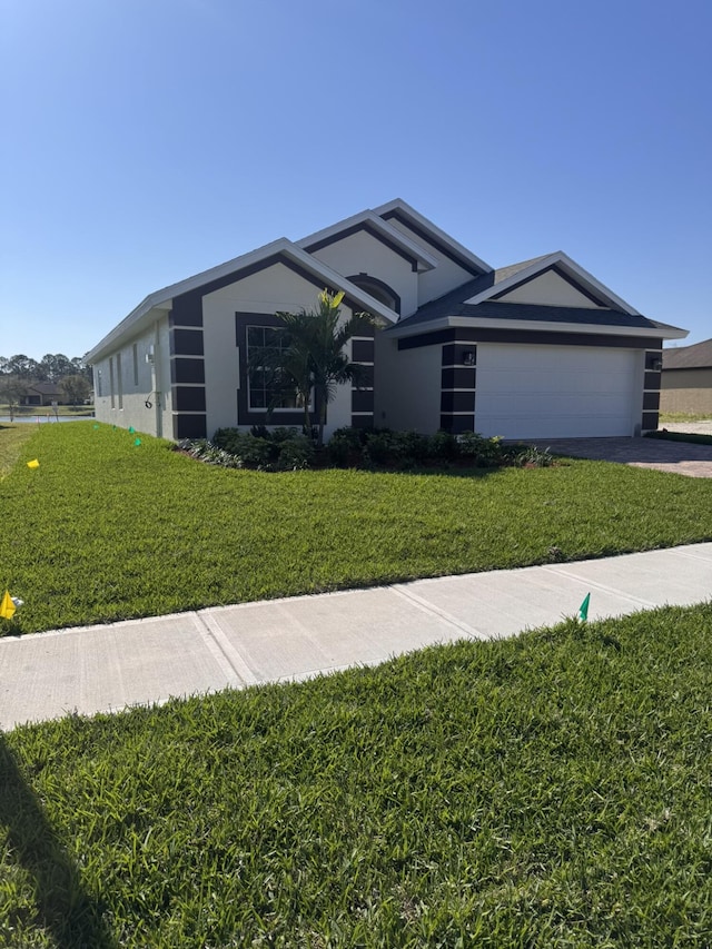 view of front of property featuring an attached garage, stucco siding, driveway, and a front yard