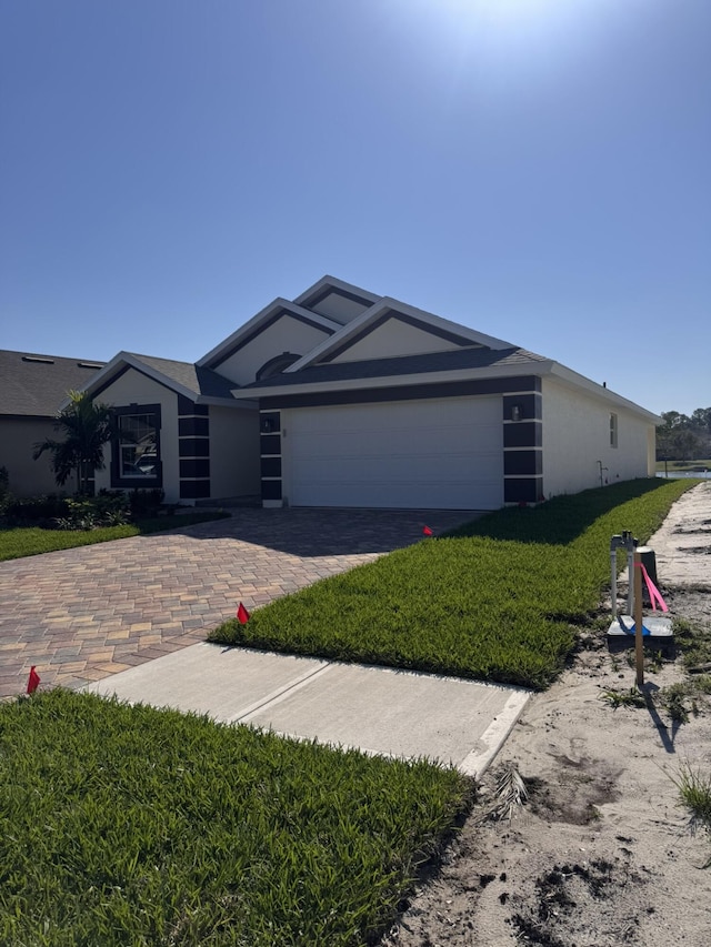 view of front of house featuring a front lawn, decorative driveway, an attached garage, and stucco siding