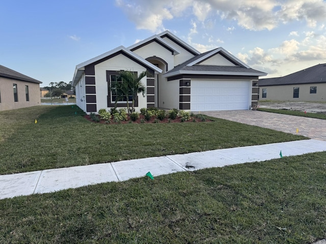 ranch-style house featuring a front yard, decorative driveway, an attached garage, and stucco siding