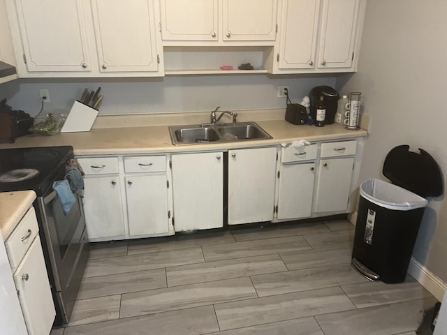 kitchen with white cabinets, stainless steel range with electric stovetop, and sink