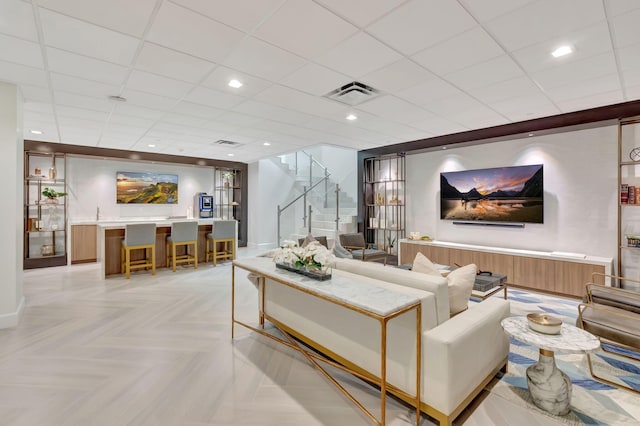 living room with a paneled ceiling and light parquet flooring