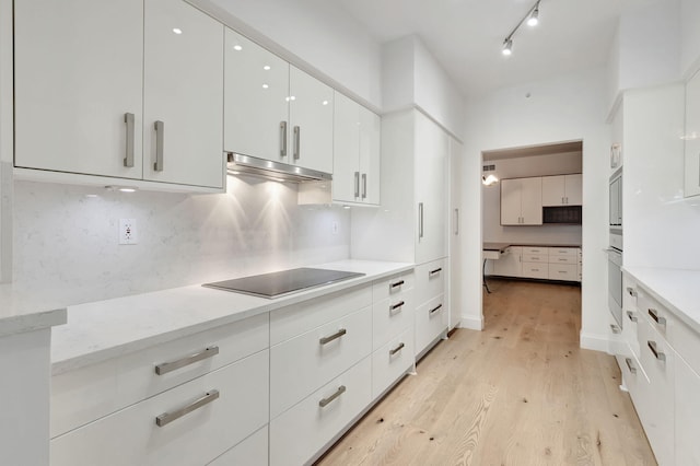 kitchen featuring white cabinets, black electric cooktop, backsplash, and light hardwood / wood-style flooring