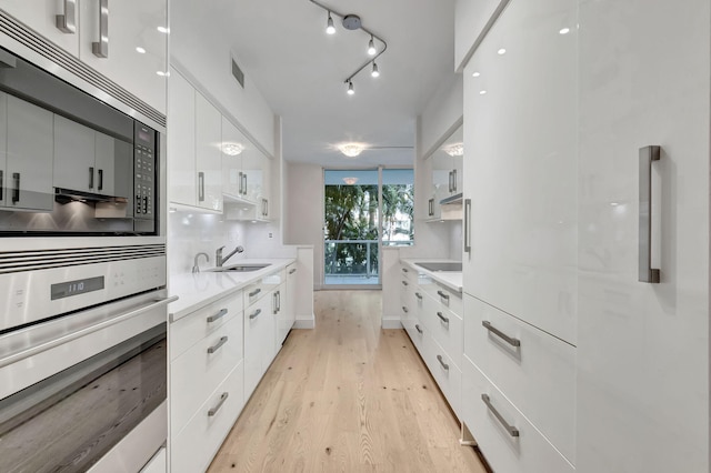 kitchen featuring oven, white cabinetry, and sink