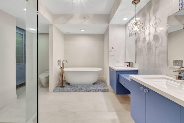 bathroom with a bathing tub, vanity, toilet, and tile patterned floors