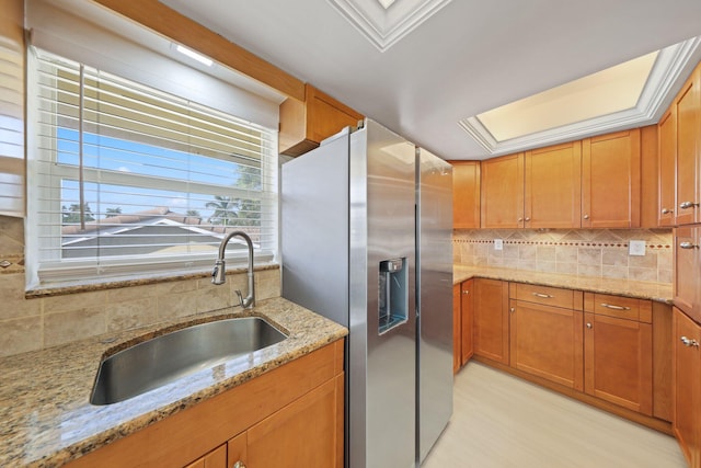 kitchen with light stone countertops, stainless steel fridge with ice dispenser, tasteful backsplash, and sink