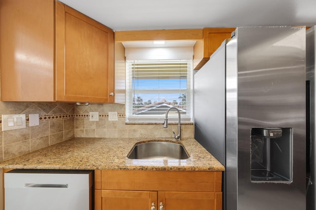 kitchen featuring decorative backsplash, light stone counters, sink, dishwasher, and stainless steel fridge with ice dispenser