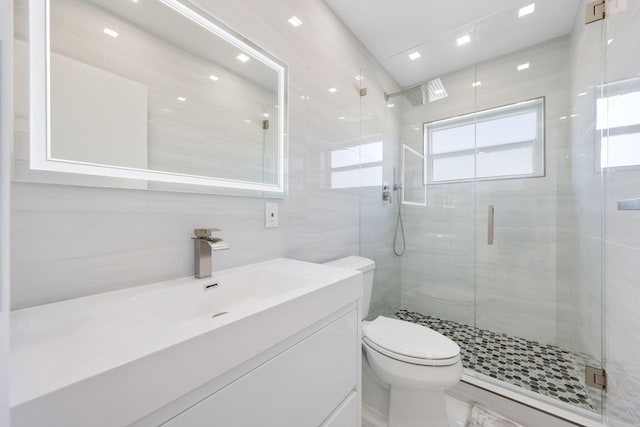 bathroom with tile walls, vanity, an enclosed shower, and toilet