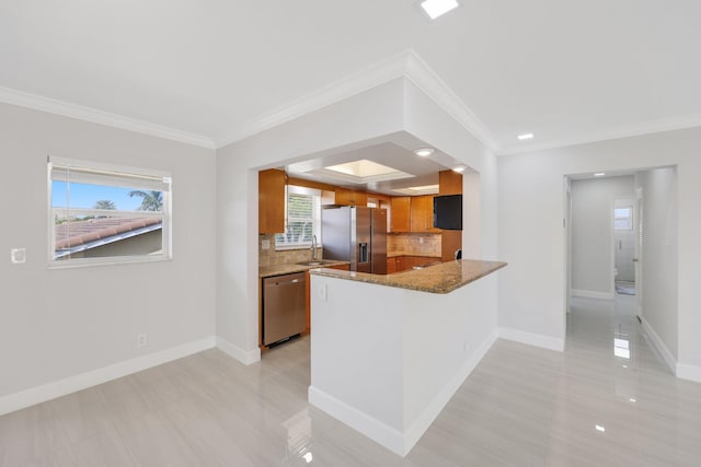 kitchen with kitchen peninsula, ornamental molding, stainless steel appliances, sink, and stone countertops