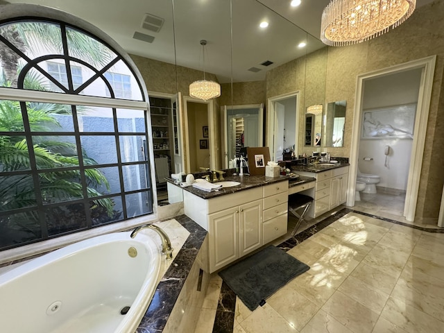 bathroom with a chandelier, vanity, a relaxing tiled tub, and toilet