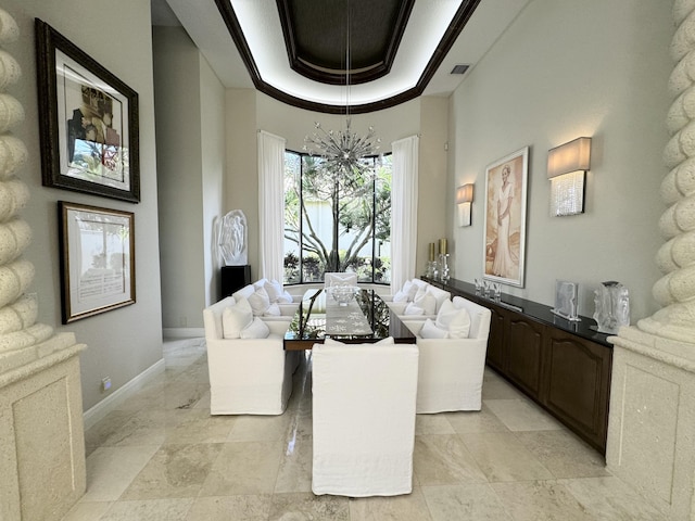 living room with a towering ceiling, a tray ceiling, an inviting chandelier, and ornamental molding