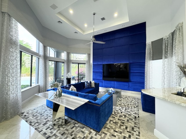 living room with a tray ceiling and ceiling fan