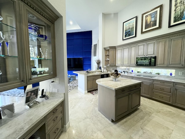 kitchen featuring sink, light stone counters, kitchen peninsula, a kitchen island, and black appliances