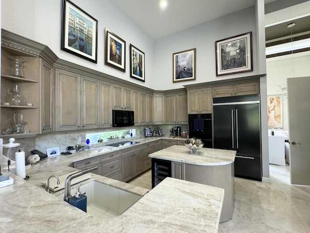 kitchen with light stone counters, a center island, beverage cooler, and black appliances