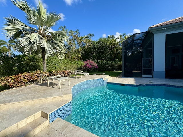 view of swimming pool featuring glass enclosure and a patio area